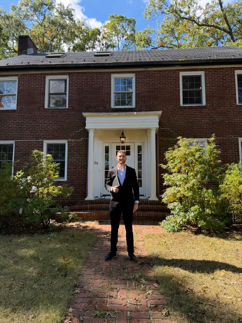 Jared standing on the brick walkway of a brick colonial home