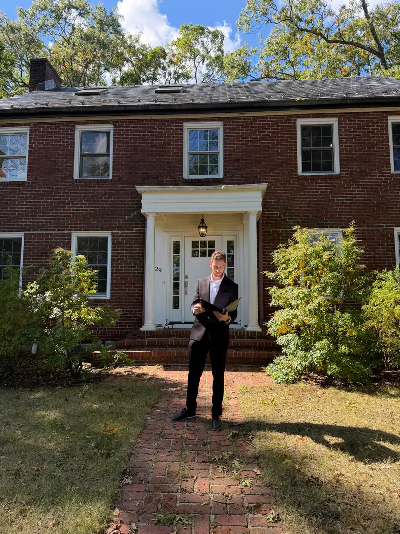 Jared reviewing a folder outside the front door of a brick colonial home
