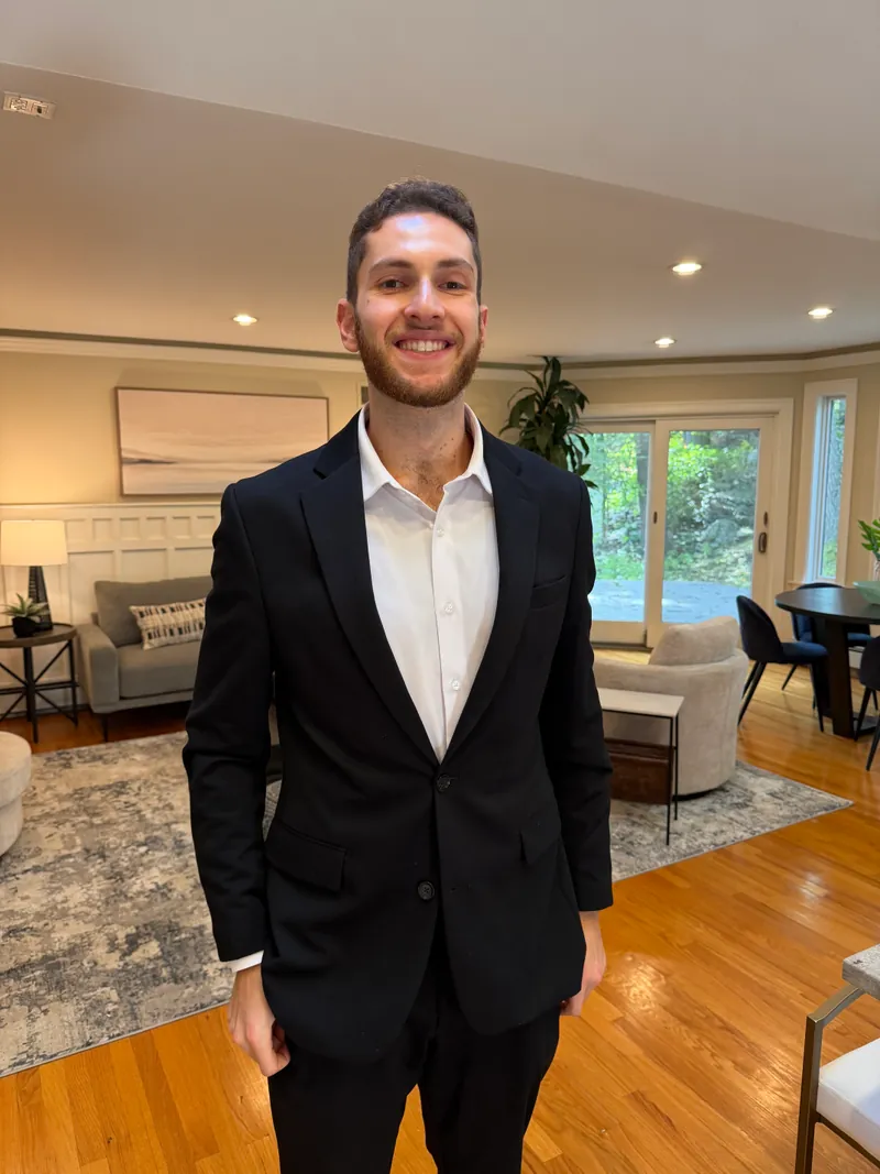 Jared Cohen smiling in a dark suit in a bright living room