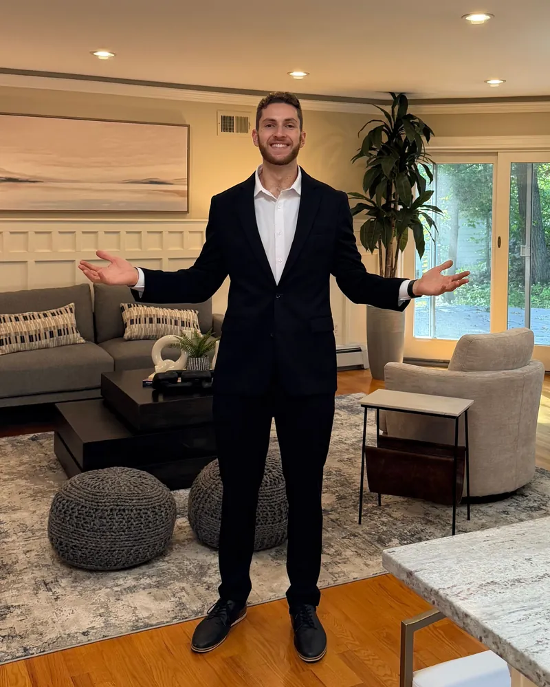 Jared Cohen, REALTOR®, smiling with his arms open in a bright living room